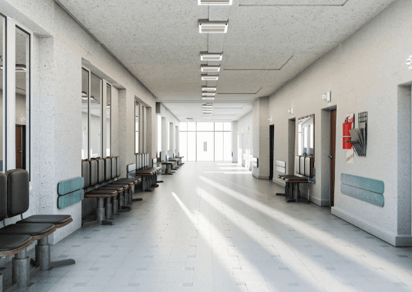 Corredor longo e vazio de uma clínica médica com fileiras de cadeiras de espera.