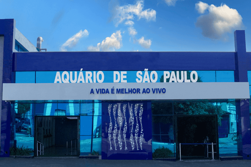 Fachada azul e moderna com a placa de identificação da entrada do Aquário de São Paulo.