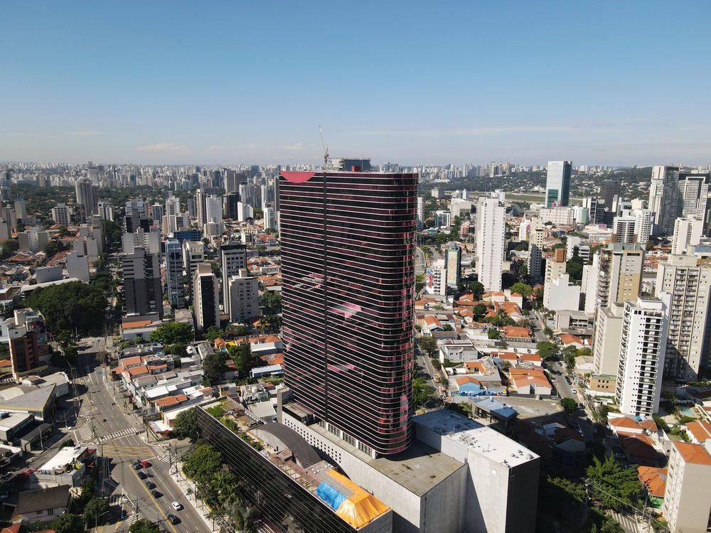 Vista aérea do moderno edifício de vidro com detalhes em vermelho do Instituto Tomie Ohtake.