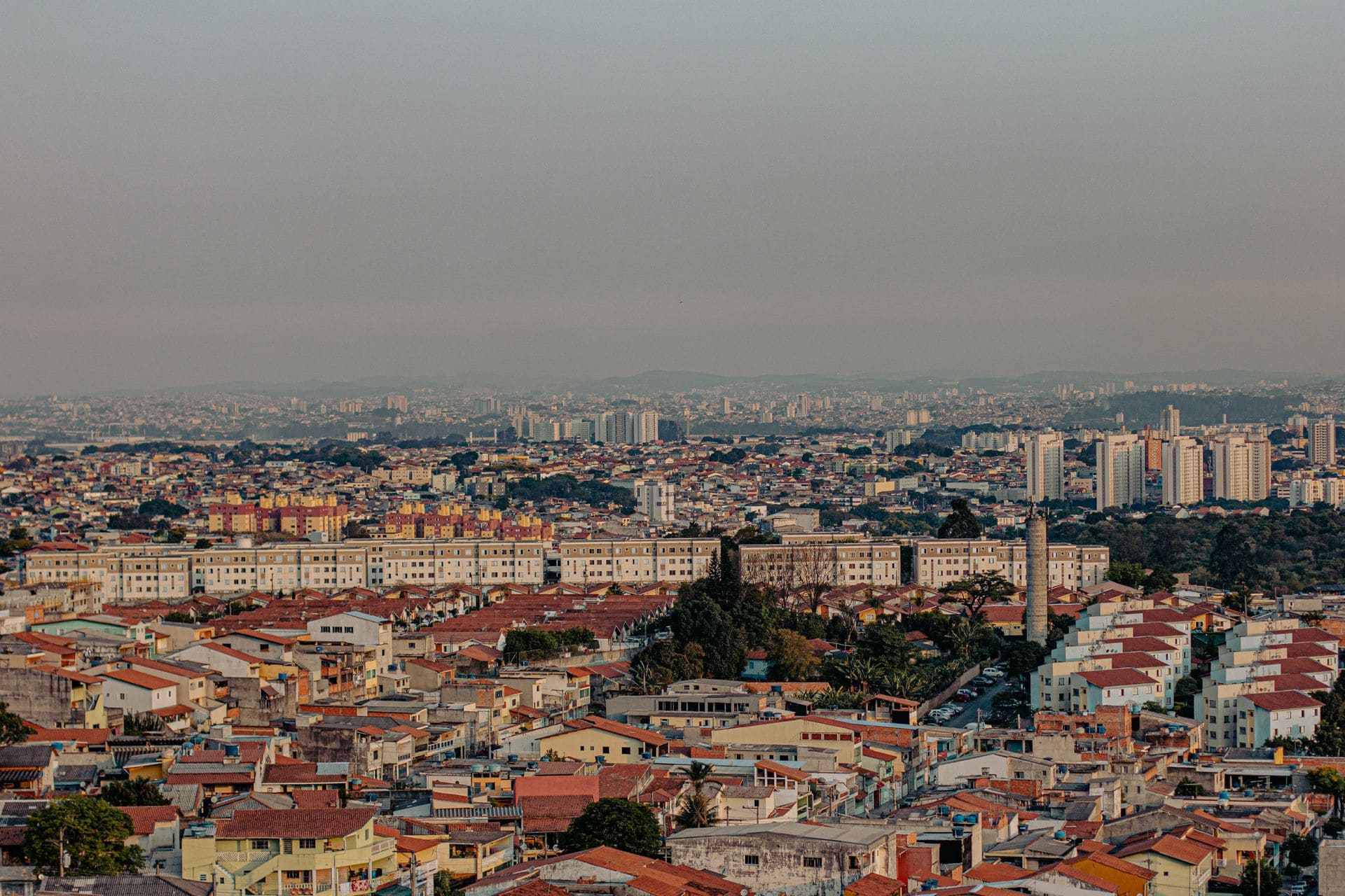 : Vista panorâmica de uma área urbana com casas e prédios ao fundo.